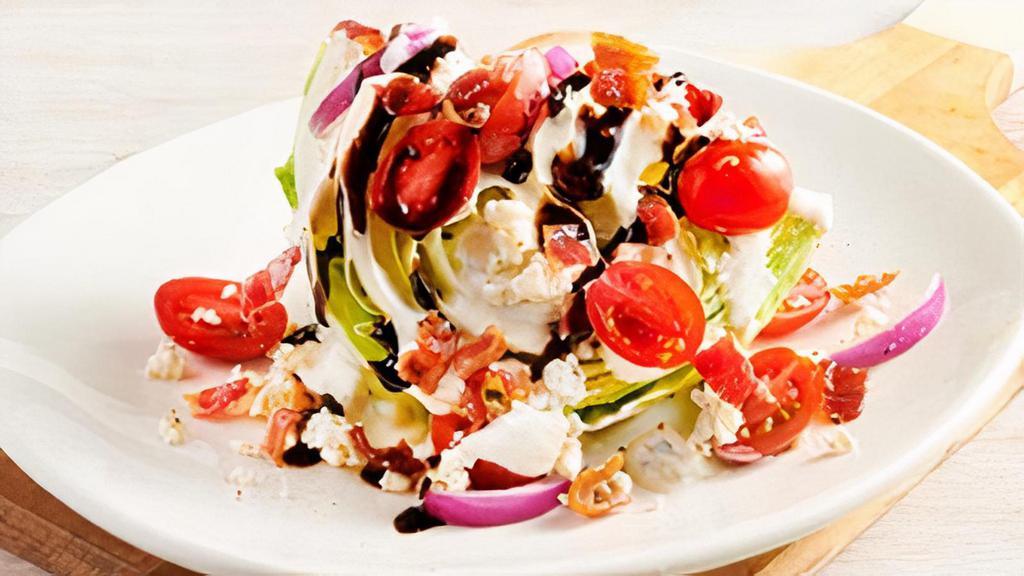 Classic Blue Cheese Wedge Side Salad · A cool, crisp wedge of fresh iceberg lettuce, chopped bacon, grape tomatoes, red onions, Blue Cheese dressing and Blue Cheese crumbles and topped with a sweet balsamic glaze.