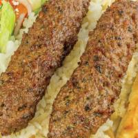 Beef Kebab · Grilled ground beef skewers served with rice, salad, sauces and pita bread,