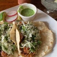 Tacos Al Pastor · Two tacos with marinated pork in a chile pineapple sauce. Topped with cilantro, onion, and s...