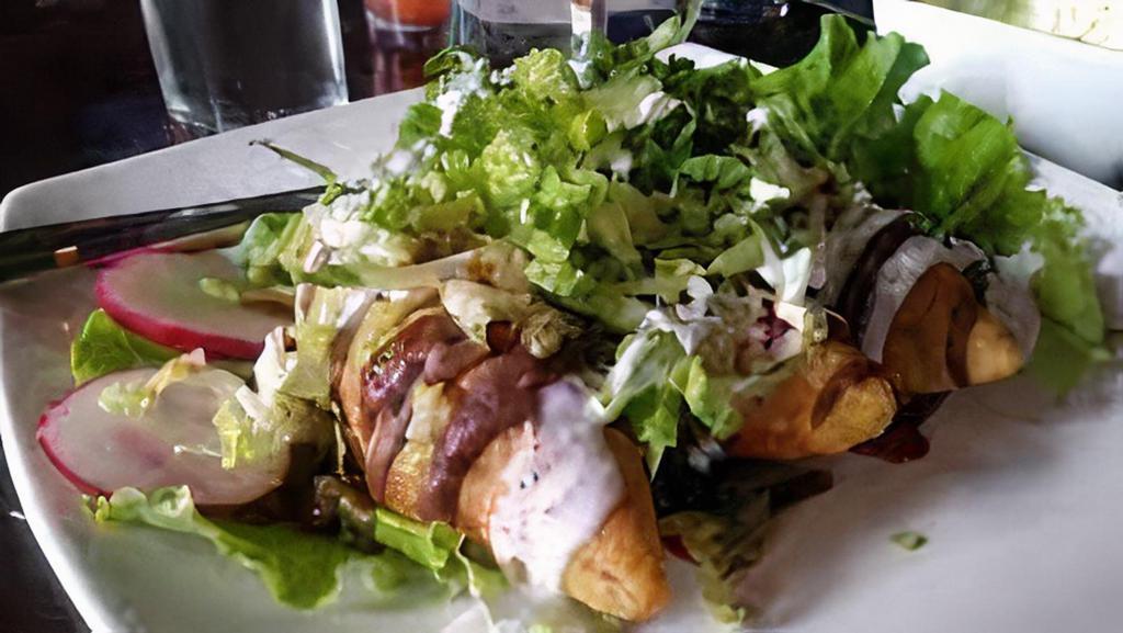 Taquitos Dorados · Three corn tortillas filled with chicken or beef rolled and deep fried. Topped with guacamole, black bean sauce, mild salsa, cream, and queso fresco.