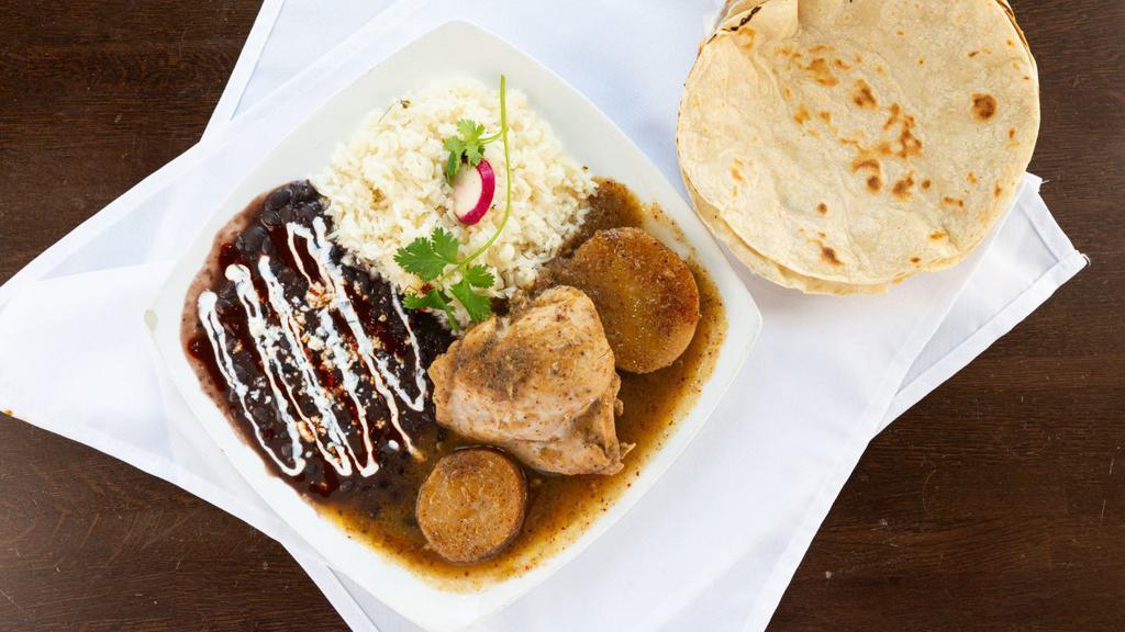 Pollo En Tomatillo · Chicken thigh bathed in a tomatillo sauce. Served with rice, beans and tortillas.