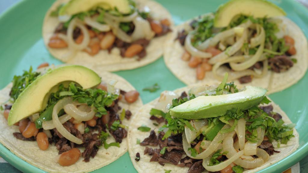 Tacos El Sol · Four soft corn tortillas filled with chopped skirt steak or grilled chicken, fresh cilantro, sliced avocados, fried jalapeño slices, onions and whole pinto beans.