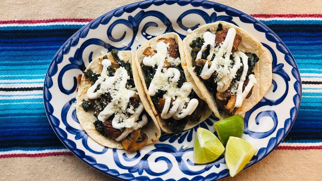 Spicy Kale & Mushroom Tacos · Spicy kale & mushrooms sauteed in chile oil, topped with crema, and cotija cheese. (spicy) (vegetarian)