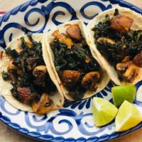 Vegan Spicy Kale & Mushroom Tacos · Spicy kale and sautéed mushrooms on three local white corn tortillas. Served with rice & bea...