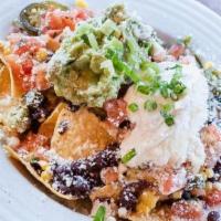 Nachos · House-made tortilla chips smothered in three cheeses, black beans, corn, jalapeños, guacamol...