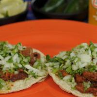 Al Pastor Taco · Thin strips of pork marinated in a red chile sauce topped with cilantro and onions