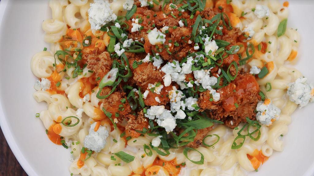 Buffalo Mac And Cheese Platforms · Pasta tossed in cheese sauce, topped with buffalo sauce and crispy chicken bites, bleu cheese crumbles and green onions.
