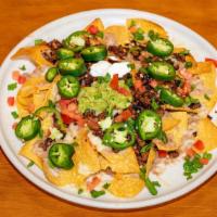 Asada Nachos · Corn tortilla chips, topped with melted cheese, tomatoes, green onions, and chopped grilled ...