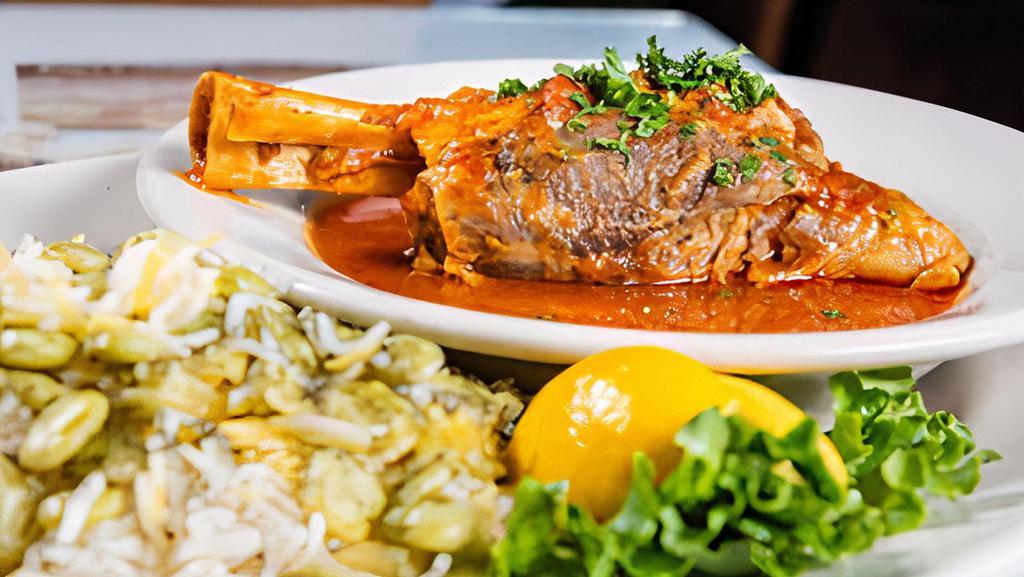 Lamb Shank Mahiche · Lamb shank slowly cooked in tomato sauce with herbs, garlic, and onions.