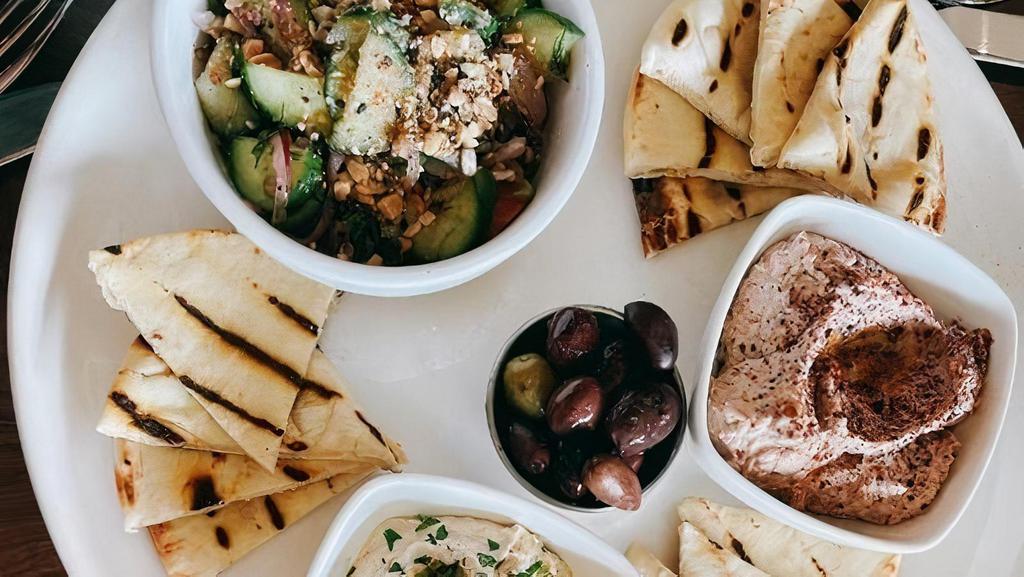 Mezze Platter · Dish is served with Baba Ghanoush, Hummus, Isreali Salad with Whipped Feta and Dukkah, Marinated Olives and Fresh Grilled Pita.