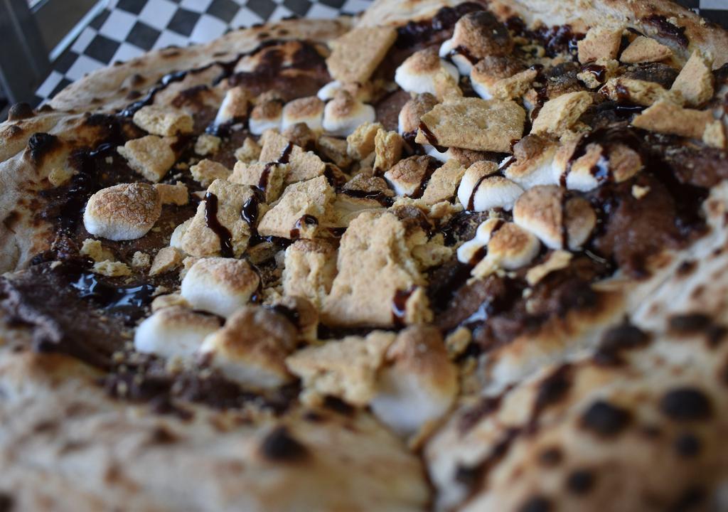 Md S’More Dessert Pizza · Hand stretched dough topped with nutella, graham cracker crumb, roasted marshmallows, and a drizzle of chocolate on top.