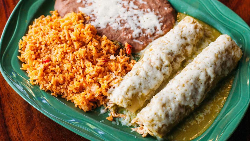 Enchiladas Suizas · Gluten-free. Two filled corn tortillas covered in sauce and melted cheese, served with rice and beans. Filled with shredded chicken and topped with green tomatillo cream sauce.