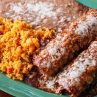 Enchiladas Poblanas · Two filled corn tortillas covered in sauce and melted cheese, served with rice and beans. Fi...