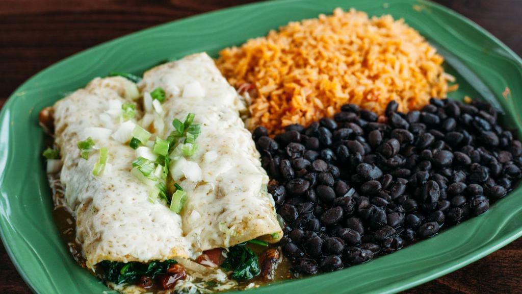 Spinach Enchiladas · Gluten-free. Two filled corn tortillas covered in sauce and melted cheese, served with rice and beans.  Filled with sautéed spinach, onions, tomatoes and topped with green tomatillo sauce and onions. Served with black beans.