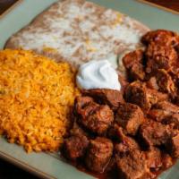 Chile Colorado · Chunks of steak cooked in chile ancho sauce. Topped with sour cream.