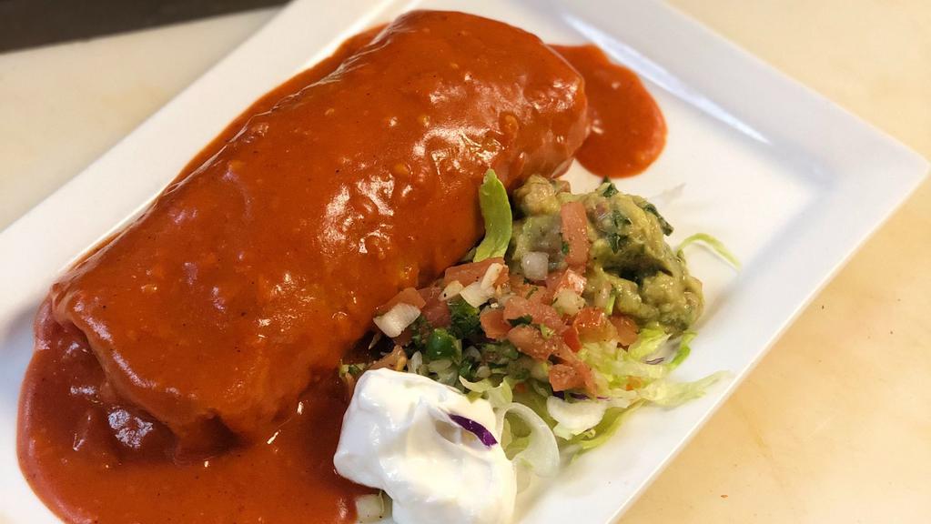 Fajita Burrito · Flour tortilla stuffed  you choice of chicken or steak, grilled onions, grilled bell peppers, rice and beans inside. Smothered  red enchilada sauce and garnished   lettuce, pico de gallo, and drizzled sour cream.