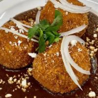 Croquetas With Mole · Three plantain breaded cakes filled with melted cheese, over mole sauce, topped with sour cr...