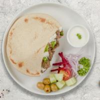 Beef Shawarma Goodness · Tender beef in a pita with tomato, cucumber, leafy greens, and white sauce.