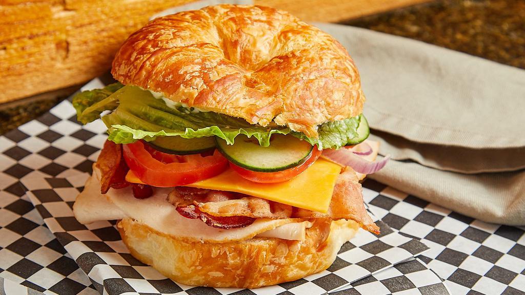 Turkey Club · Croissant, turkey, bacon, red onion, cucumber, tomato, romaine, Cheddar cheese, and mayo.