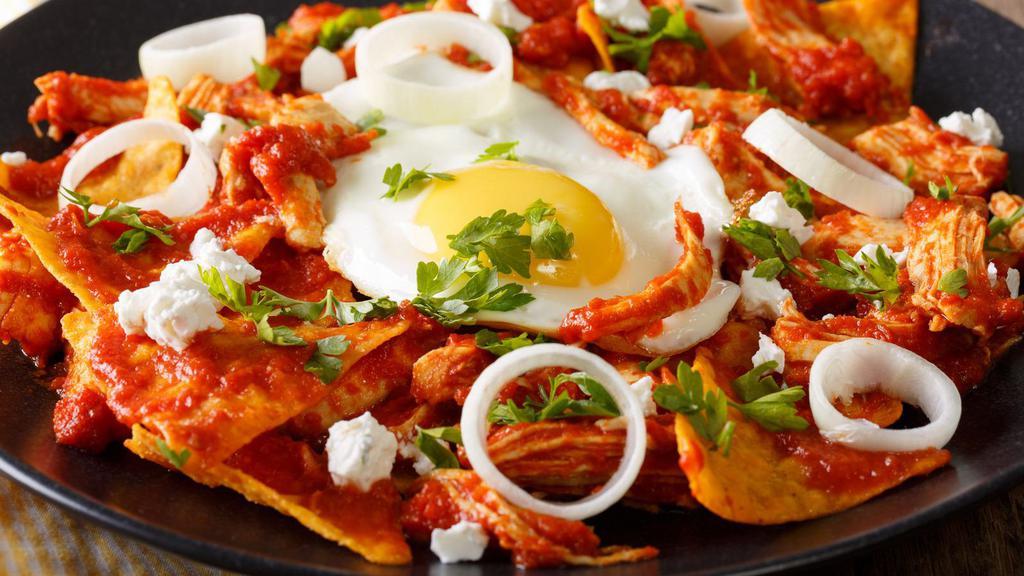 Chilaquiles · Fried corn tortilla strips topped with tomatillo salsa, cheese and sour cream, served with two eggs and refried beans.