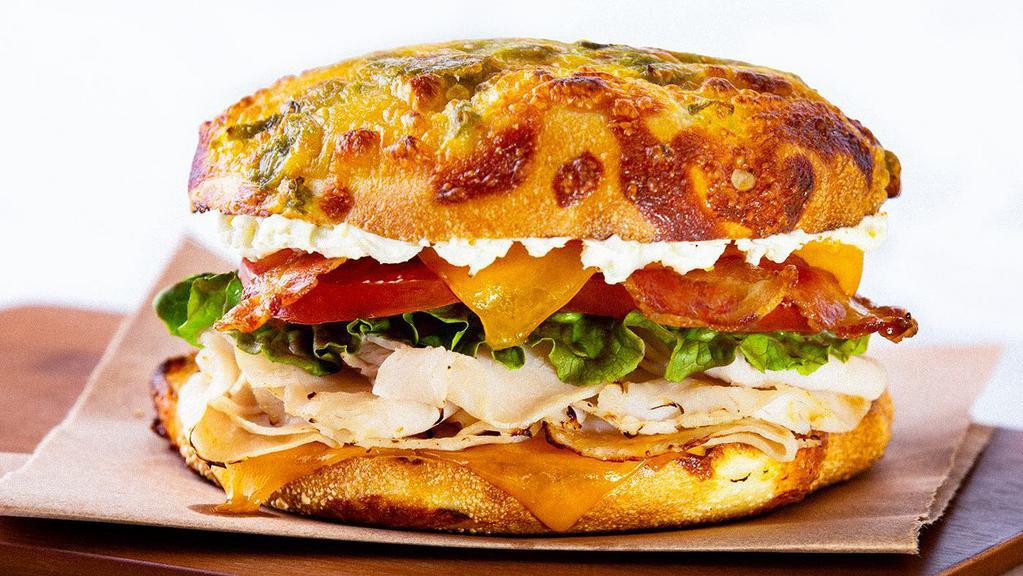 Good Vibes Turkey · A fresh-baked green chile cheese artisan roll topped with turkey, thick-cut bacon, cheddar, whipped cream cheese, lettuce, tomato and red onion.