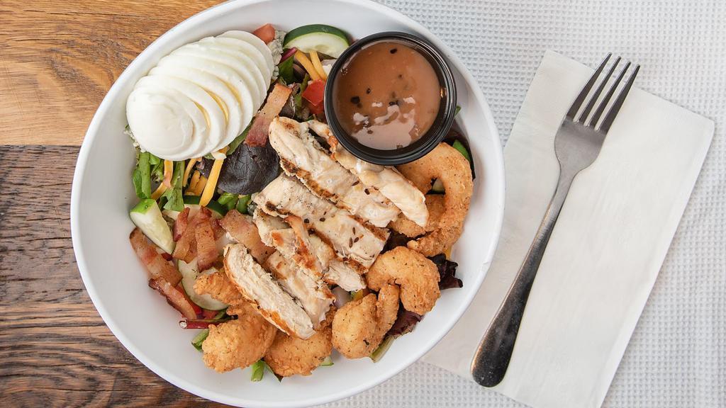 Shrimp & Chicken Cobb Salad · Fresh greens, topped with fried shrimp and grilled chicken, hard boiled egg, cheddar-jack cheese, diced tomatoes, bacon, crumbled blue cheese and red onion.