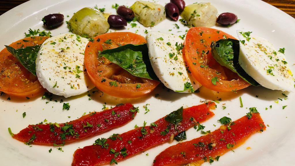 Caprese Salad · Fresh buffalo mozzarella over fresh sliced tomatoes, artichoke hearts, roasted red peppers and Kalamata olives with basil and extra-virgin olive oil.