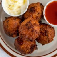Hush Puppies · Savory cornmeal with bacon, cheese and chives deep fried and served with Texas pete ketchup.