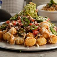 Carne Asada Tots · tots topped with asada + queso sauce + chipotle aioli + pico + jalapenos + cotija cheese