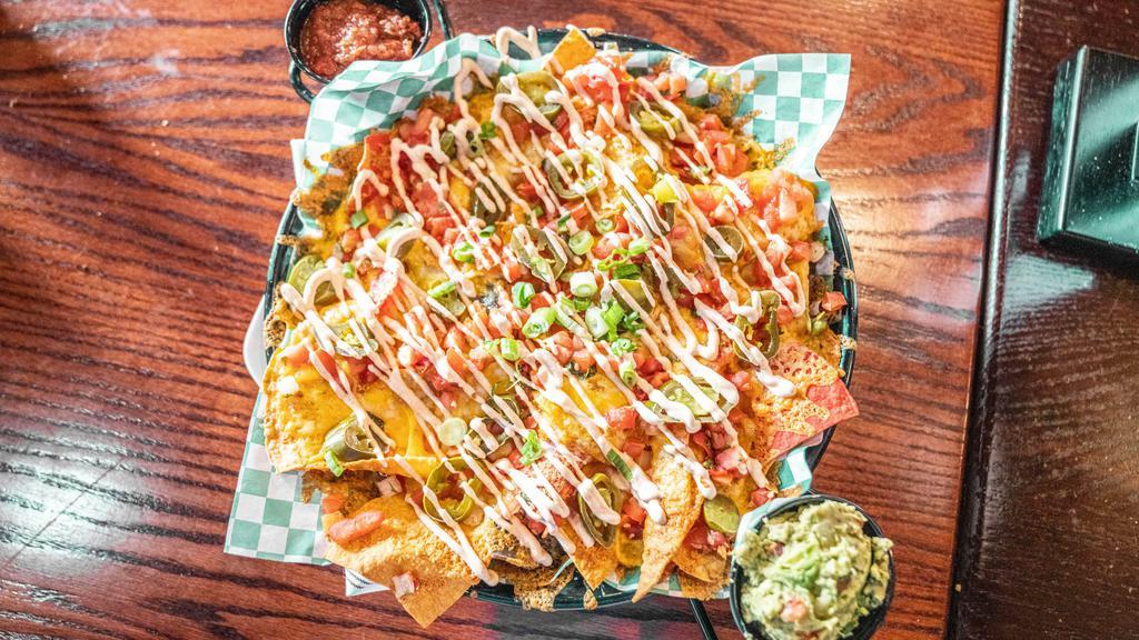 Legendary Nacho · Fresh cooked corn chips layered with Pico de Gallo, jalapeños and melted cheddar/jack cheeses finished with smoked pepper crema, green onion and fire roasted salsa.