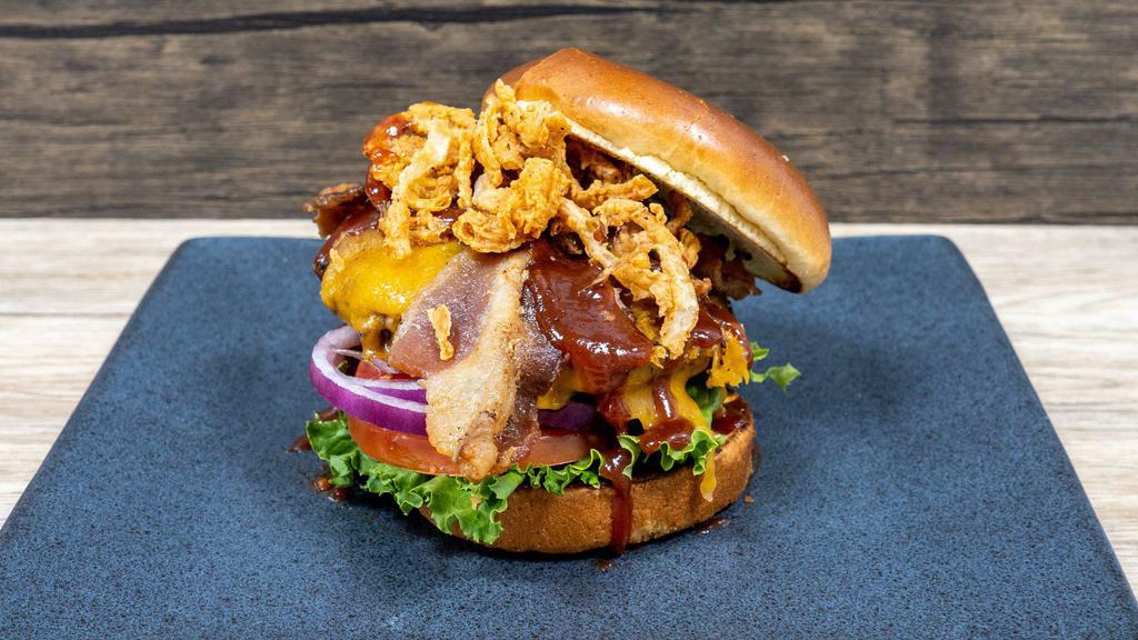 Backyard Burger · 1/2 lb. beef patty, Cheddar cheese, bacon, fried onions strings, smoked BBQ sauce, lettuce, tomato and red onions,  brioche bun, side of fries,