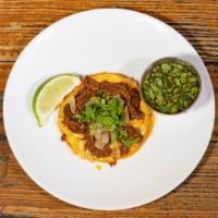 Birria  · Slow Cooked Goat . Street tacos are served with sautéed onions, cilantro and lemon on two co...