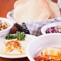 Shakshuka (Moroccan Sandwich) · Eggs poached in our special tomato sauce, fried potato slices, hummus, Israeli salad, cabbag...