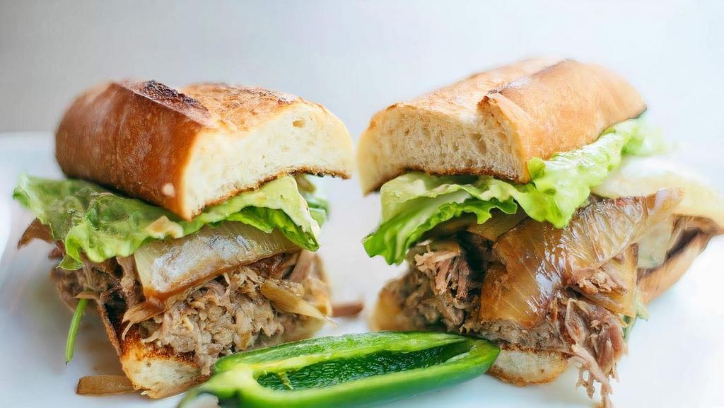 Caribbean Roast · Marinated and slow-roasted pork shoulder, fresh cilantro, pickled jalapenos, caramelized onions, and crisp romaine on a toasted baguette slathered with garlic aioli.
