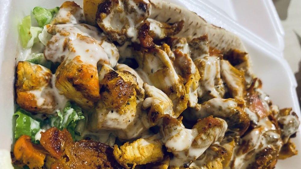 Chicken Shawarma · Marinated and flame broiled chicken with tomatoes, lettuce, cucumber pickles, garlic spread and drizzled with tahini sauce wrapped in pita bread or thin