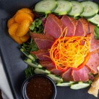 Seared Tuna Tataki Salad · Seared sashimi grade tuna over a bed of crisp mixed greens served with cucumbers, crispy won...