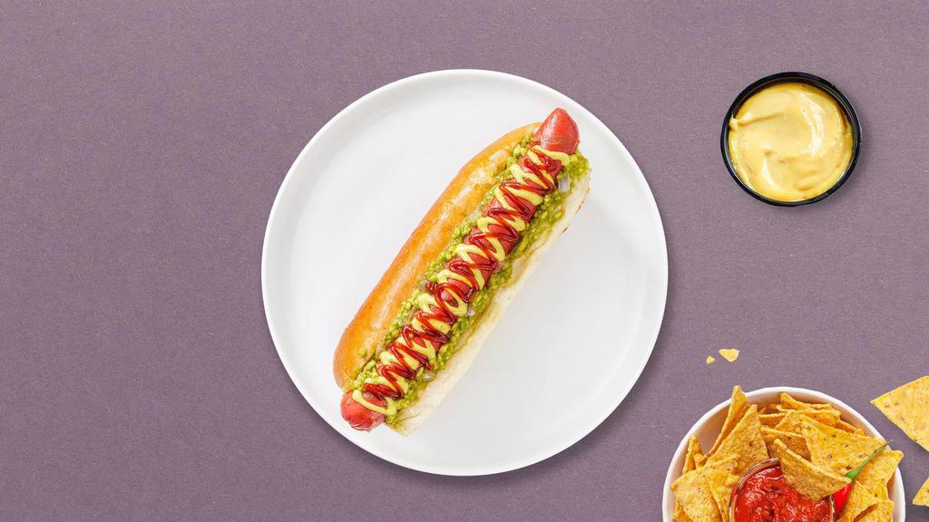 Top Loaded Vegan Dog · Vegan hot dog topped with pickles, relish, and tomato on a toasted hot dog bun.