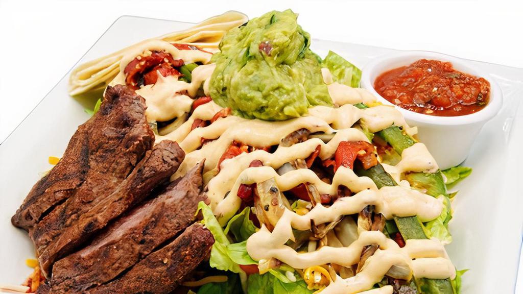 Steak Fajita Salad · Charred Filet, Romaine, diced tomatoes, cheddar jack cheese, grilled red and green bell peppers, roasted white onions, served with our house-made salsa, guacamole and chipotle sour cream. Served with a warm flour tortilla, Choice of dressing.