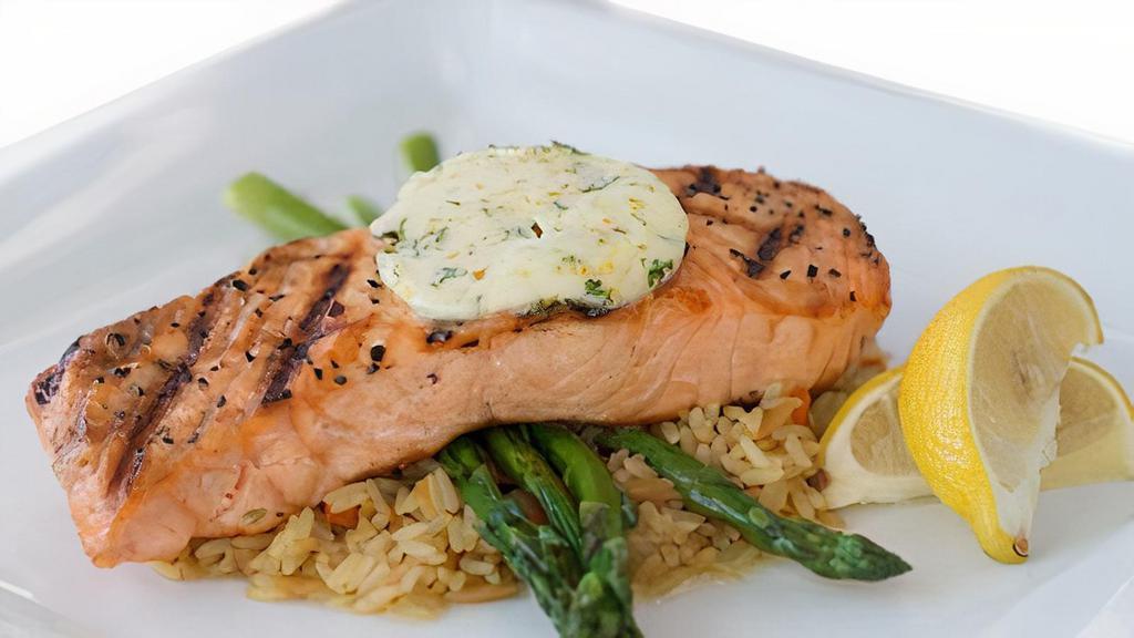 Grilled Atlantic Salmon · Broiled salmon filet topped with citrus butter on a bed of rice pilaf and served with grilled asparagus