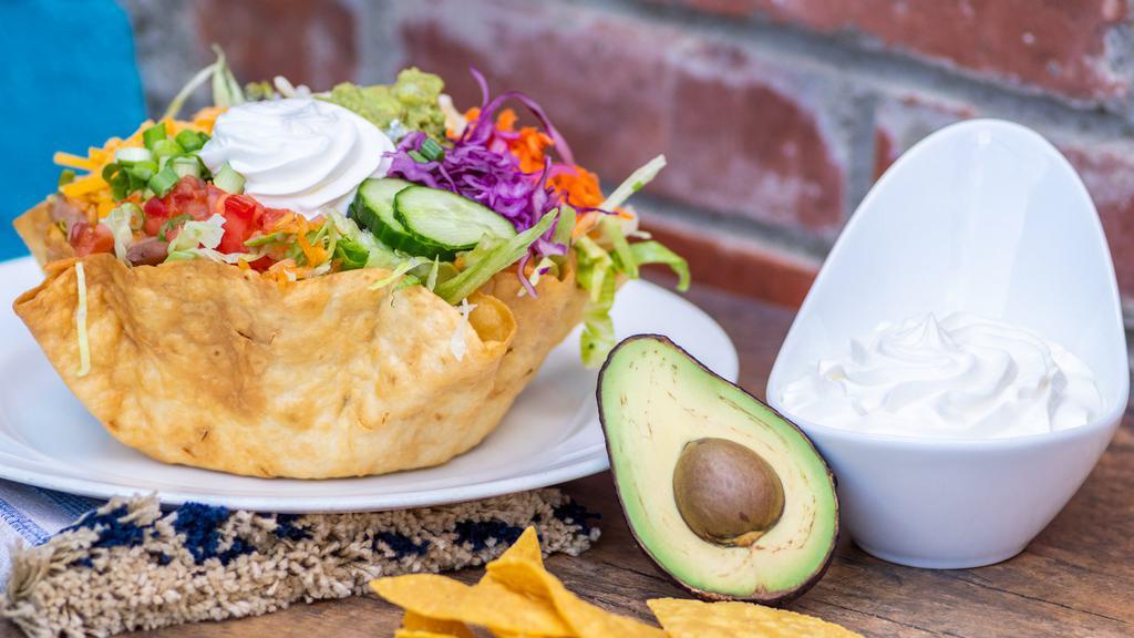 Veggie Taco Salad · Vegetarian. Flour shell filled with lettuce, rice, whole beans, green onions, sour cream, guacamole, tomatoes, cheese, carrots, and cucumber.