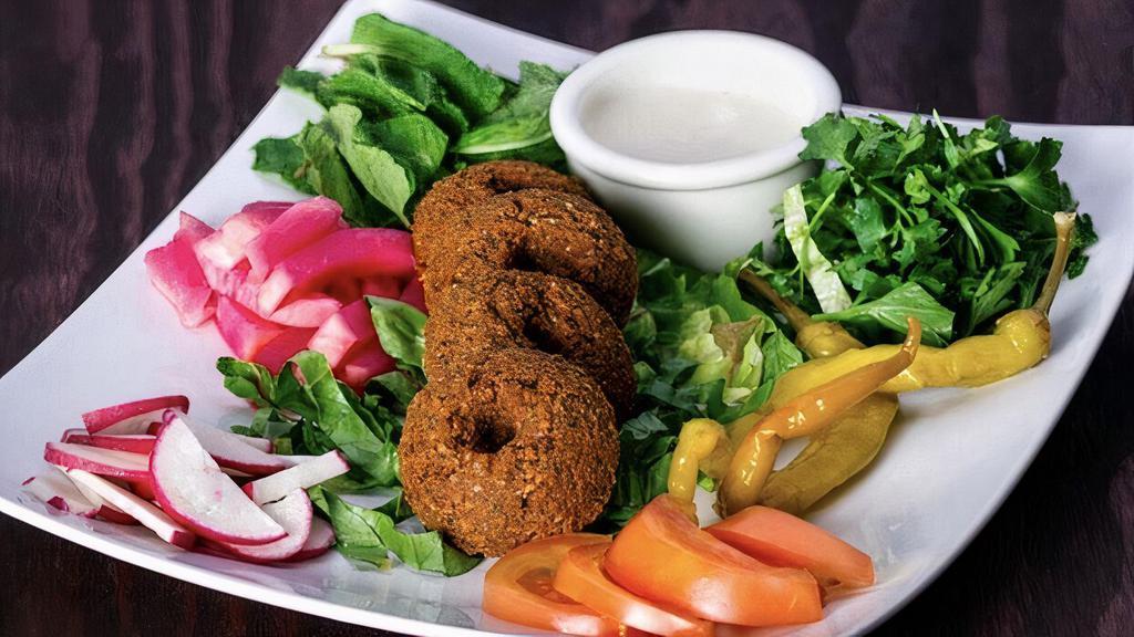 Falafel · Gluten-free,Vegan. Mix of crushed garbanzo beans, fava beans, garlic and onion mixed with delicious and aromatic spices and sesame seeds served with tahini sauce and fresh vegetables.
