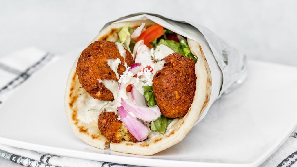 Falafel Sandwich · Falafel and hummus with lettuce, tomatoes, red onions, feta cheese and tahini sauce wrapped in pita bread.