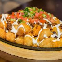 Tachos · Nachos but with golden crispy tater tots. Loaded with ground beef, black beans, shredded che...