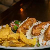 Tanya'S Fish Tacos · Three grilled flour tortillas filled with cut beer battered cod topped with fresh slaw, chee...