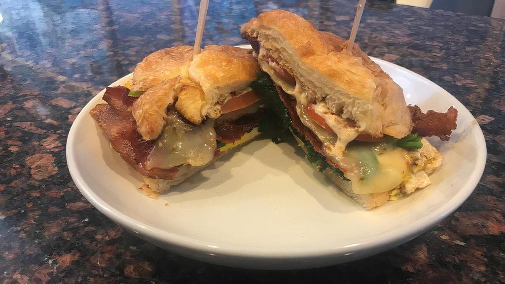 Zesty Breakfast Sandwich · Two over medium eggs together with pepper jack cheese, tomatoes, spinach and bacon and placed on a buttery toasted croissant.