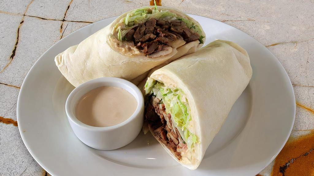 Lamb Shawarma Sandwich · Original hummus, grilled lamb marinaded with garlic, lemon juice and traditional spices, served on our house pita bread with lettuce, tomatoes, parsley, sauted onions, and our garlic tahini sauce.