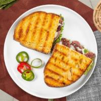 Philly Steak Panini · Griddled sandwich with chopped steak, melted yellow cheddar cheese, caramelized onions, saut...