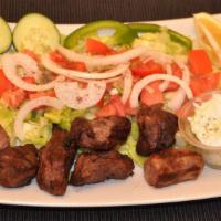Lamb Tikka Over Salad · Two skewers with salad and tzatziki sauce.