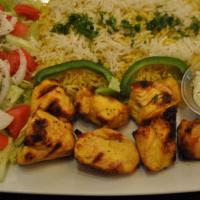 Chicken Tikka Over Rice · Two skewers with rice, salad and tzatziki sauce.