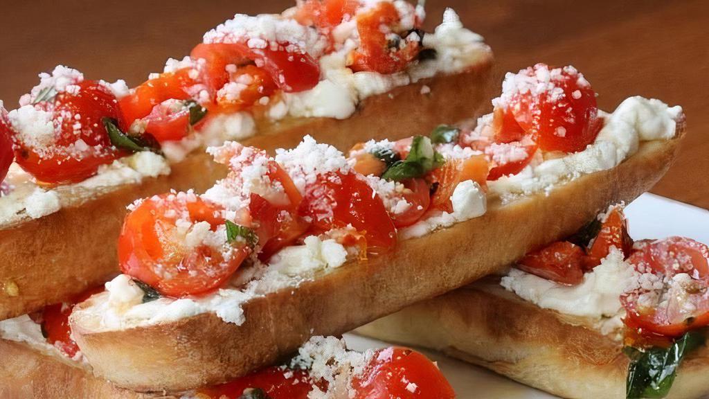 Goat Cheese Bruschetta · Thick cut toasted French baguette slices with goat cheese, tomato + fresh basil, drizzled with olive oil